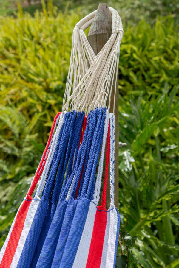 Detalles de un asa de una hamaca hecha a mano en Colombia. También vemos el detalle del tejido de los hilos de colores azul, blanco y rojo.