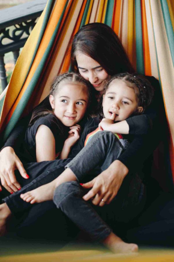 Une femme et ses enfants dans un hamac de couleur terracotta