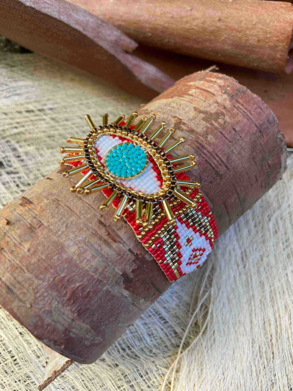 Un bracelet artisanal rouge de Colombie tissé en perles avec un motif central en forme d'œil.