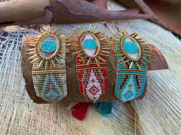 Des bracelets artisanaux beige de Colombie tissé en perles avec un motif central en forme d'œil.